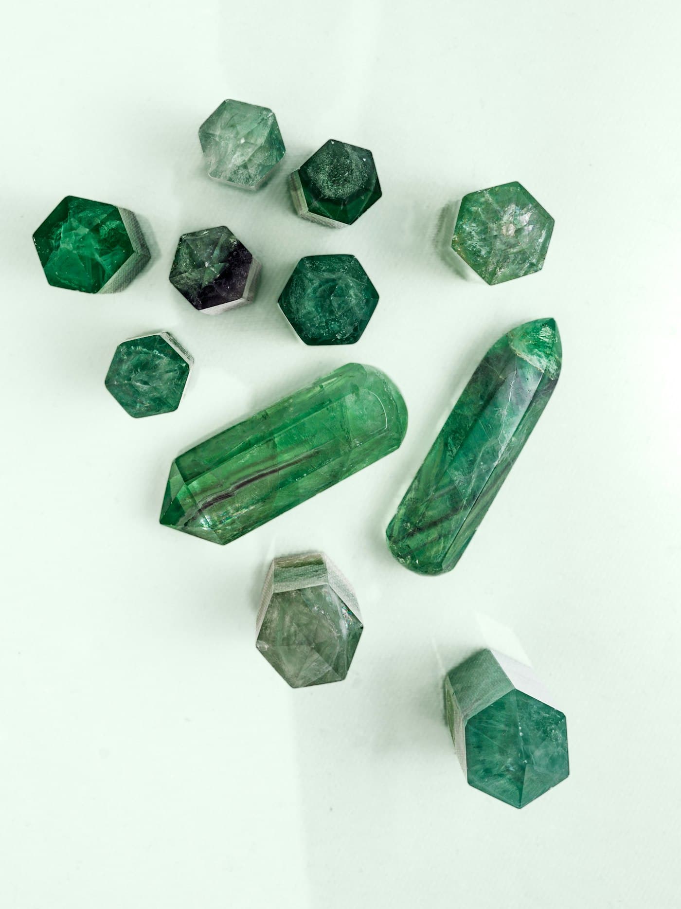 Small green crystals laid out on a pale surface, as if gathered for selection