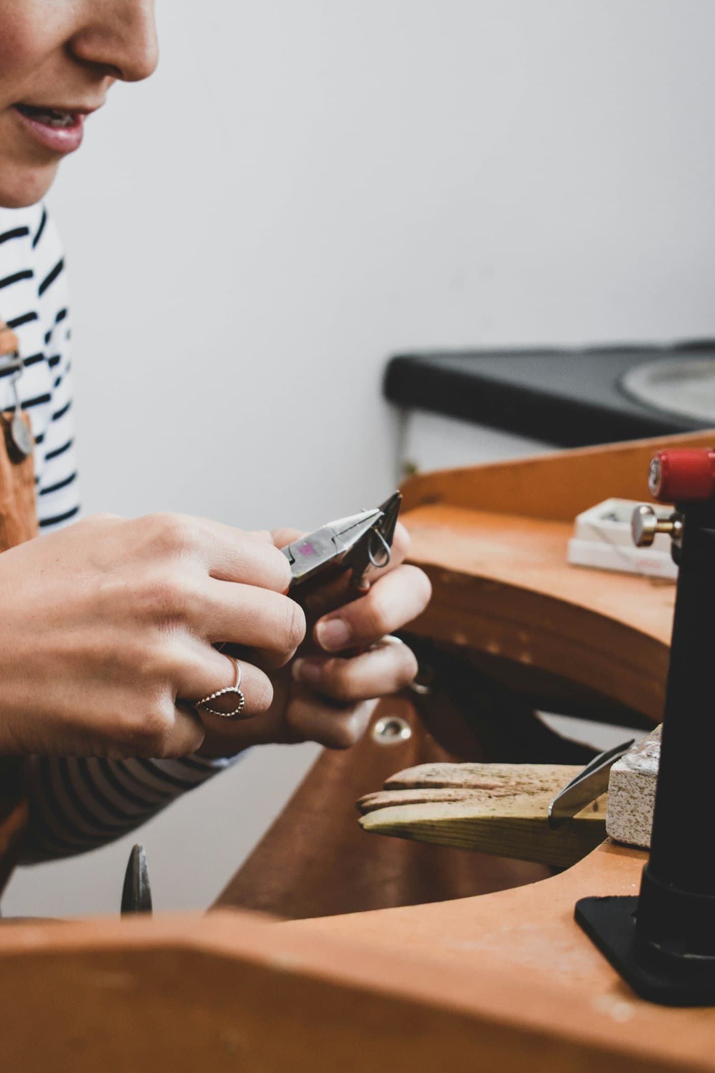 A jeweller at a bench working on a piece by hand