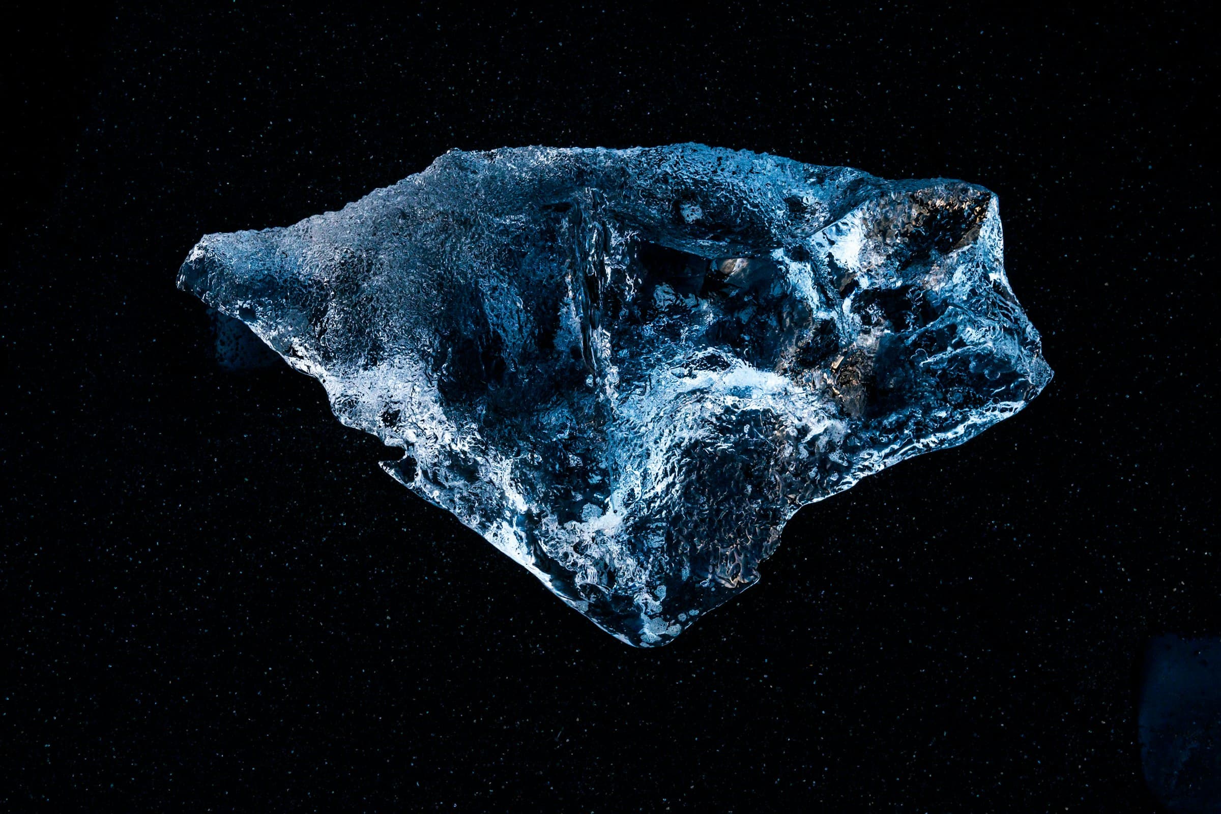 A rough blue natural gemstone catching the light against a dark background