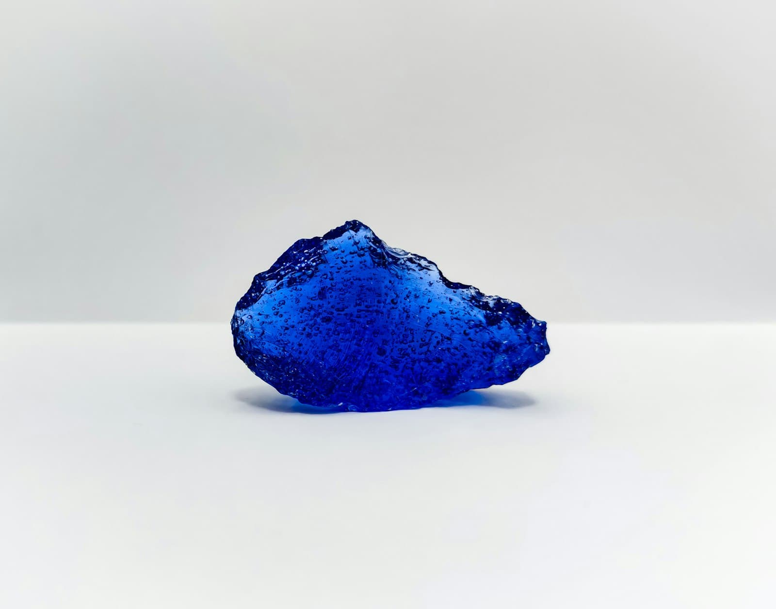A rough blue gemstone resting on a pale surface